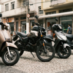Fila de scooters e motos elétricas estacionadas em uma rua de comércio, sugerindo a escolha entre modelos