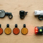 Equipamentos obrigatórios da bicicleta elétrica sobre uma bancada: campainha, retrovisor, luzes e refletivos